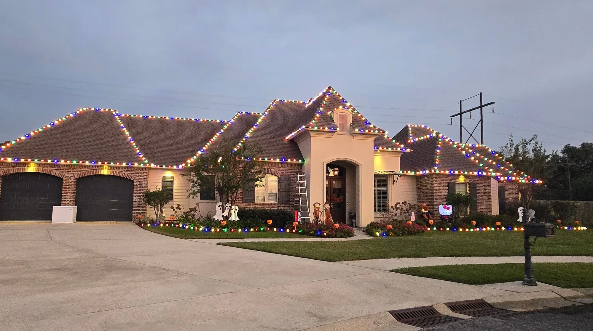 Acadian home at dusk with warm-white roofline lights and multicolor pathway and landscape lighting