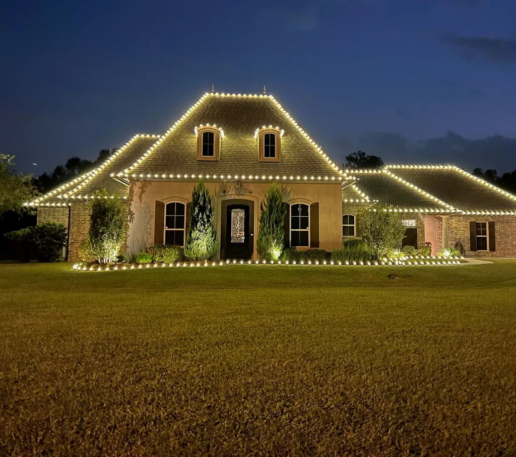 Brick Acadian home at twilight with warm-white roofline lighting