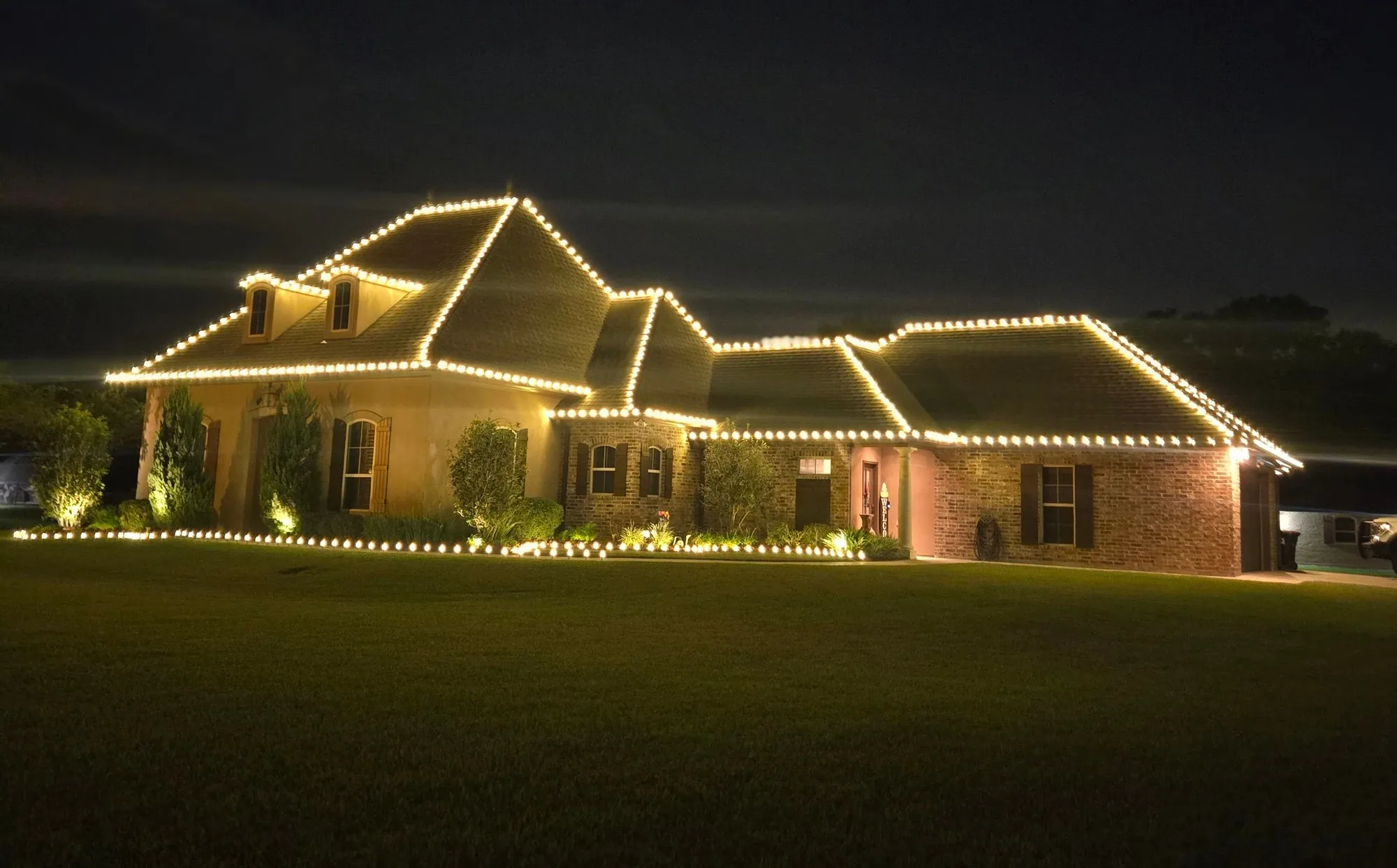 Single-story ranch home at night outlined in warm-white roofline lights